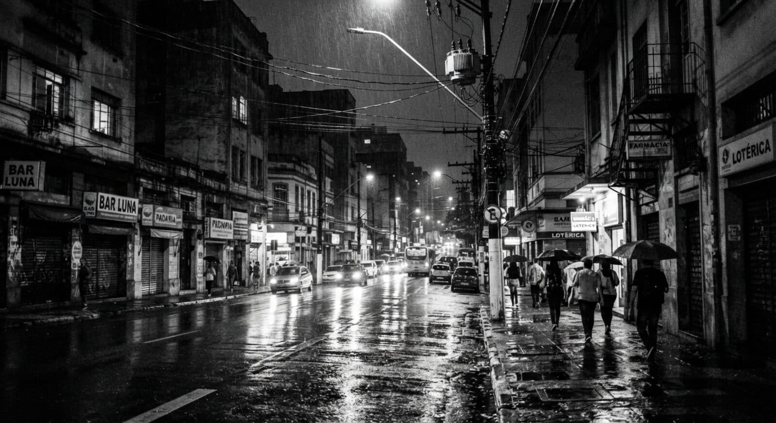 Rua de uma cidade brasileira à noite, sob chuva